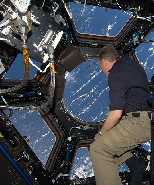 Astronaut on ISS looking through the Cupola module windows